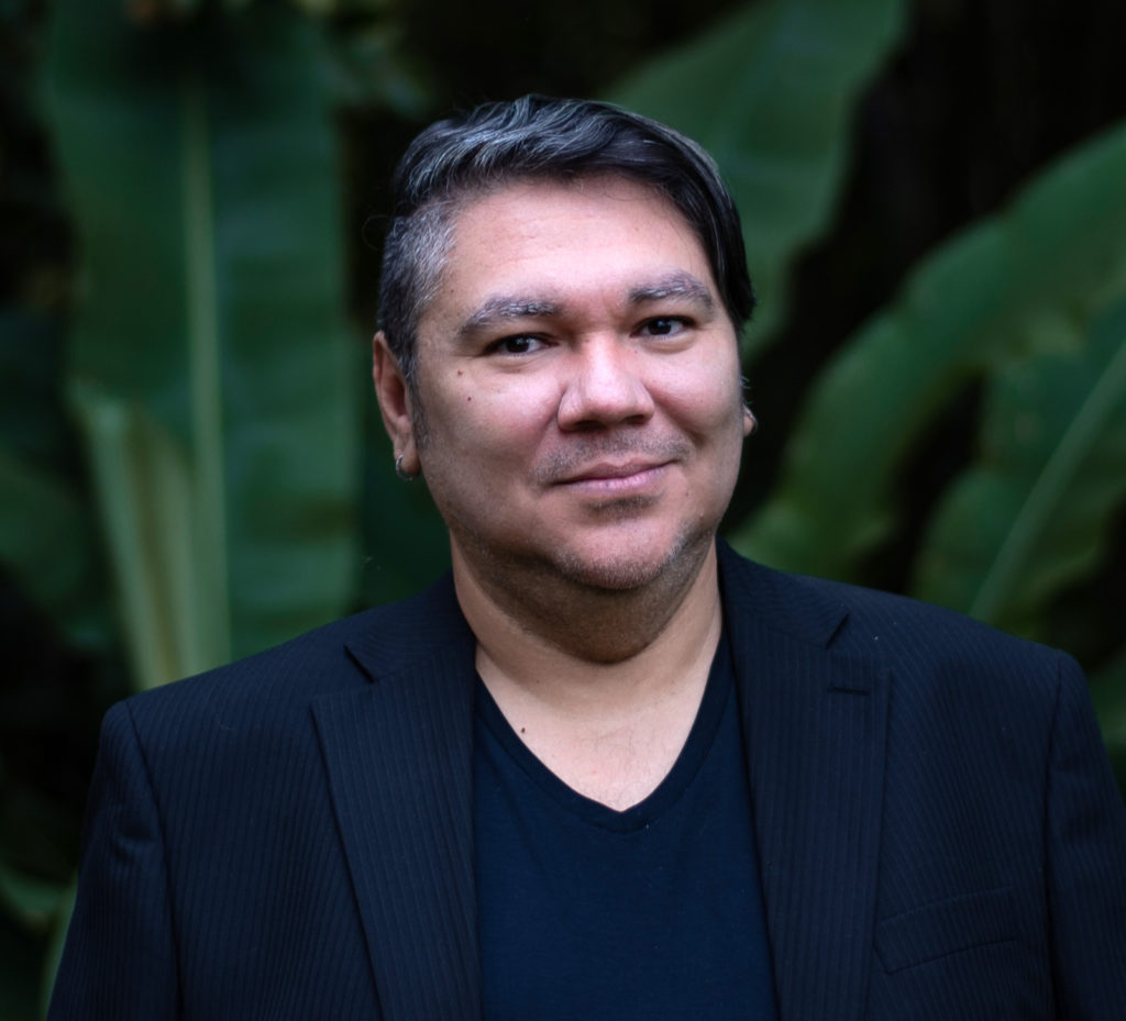 Headshot of a man in front of large leaves